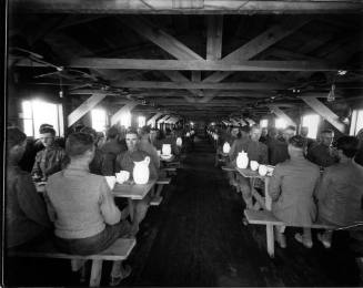 Black and white photo. Soldiers wait to eat at the mess hall at Camp Funston, Photo by Milner Studios, 1917. Albuquerque Museum, gift of Bob Davis, Object number PA1992.005.586.